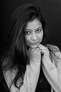 Close-up portrait of young woman against gray background