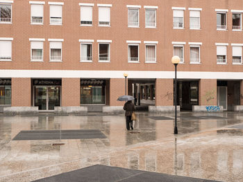 Man walking on street against building in city