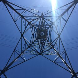 Low angle view of electricity pylon against blue sky