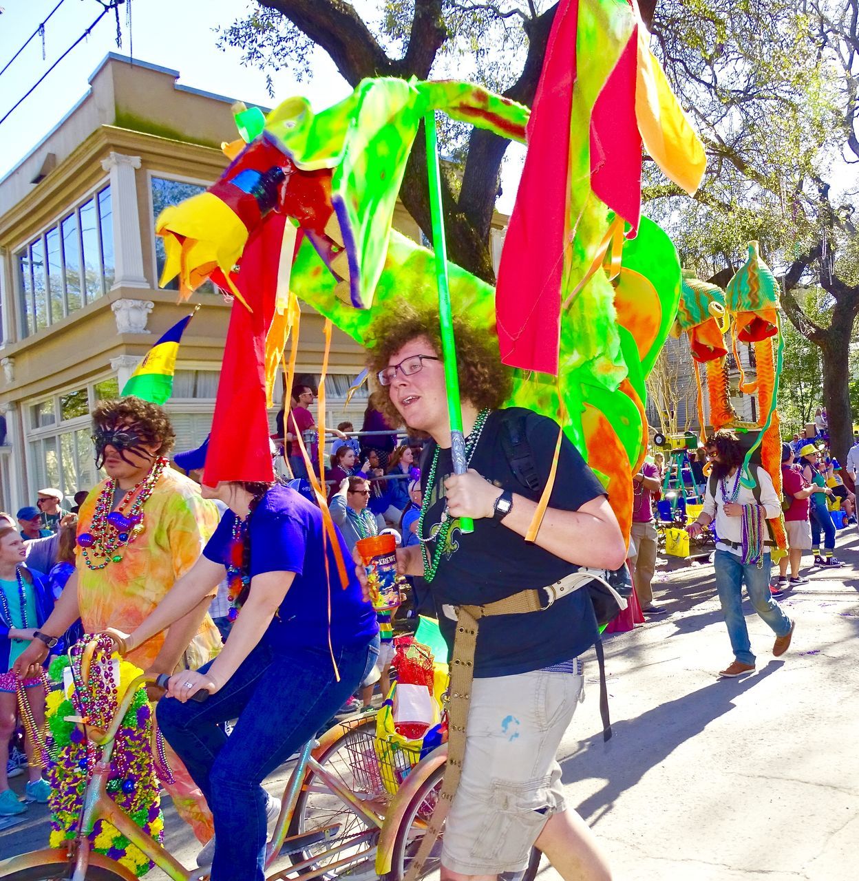 real people, day, large group of people, lifestyles, multi colored, holding, leisure activity, men, outdoors, celebration, enjoyment, flag, standing, togetherness, happiness, architecture, building exterior, women, tree, powder paint, young adult, holi, adult, people