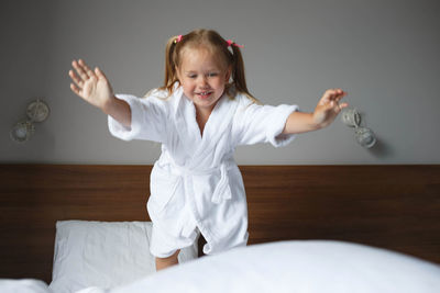 Smiling girl jumping on bed at home