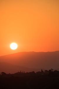 Scenic view of silhouette landscape against orange sky