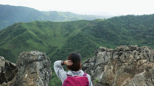 Rear view of woman looking away while standing against landscape