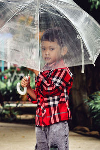 Boy holding umbrella during rainy season