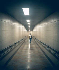 Rear view of person walking in subway tunnel