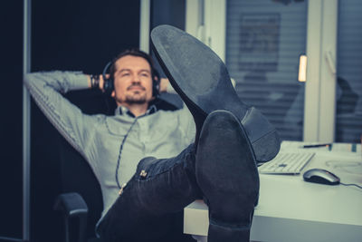 Businessman listening music while relaxing in office