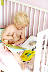 Girl in cot looking at books