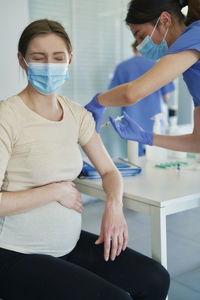 Female doctor giving vaccination to pregnant patient at clinic