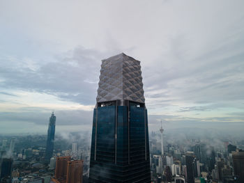 Modern buildings in city against cloudy sky