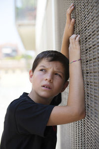 Teenager boy looking away while standing by wall