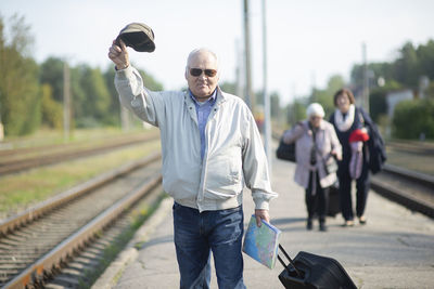 Portrait of senior elderly man holding hat and map,waiting  train traveling journey during pandemic