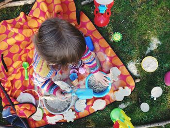 High angle view of girl playing with sand and toys on grass