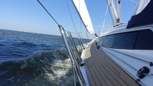 Ship sailing in sea against clear blue sky