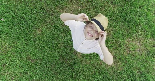 High angle portrait of smiling girl wearing hat while standing on grassy field