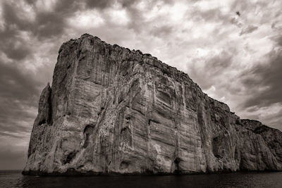 Low angle view of rock formation against cloudy sky