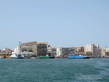 Sea by buildings against clear sky