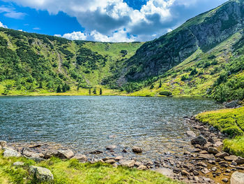 Scenic view of river by mountains against sky