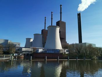 Factory by lake against sky