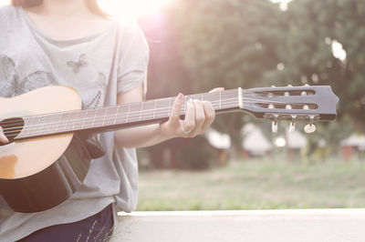 Midsection of man playing guitar