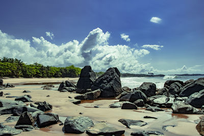 Scenic view of rocks on shore against sky