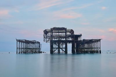 Abandoned pier over sea against sky during sunset