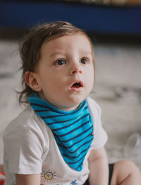Portrait of cute boy wearing baby bib and looking with surprise 