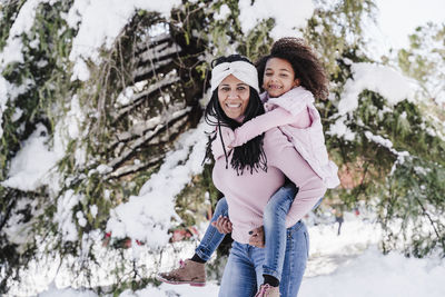 Portrait of smiling woman with snow covered trees during winter