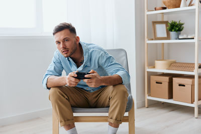 Young man using mobile phone while sitting on sofa at home