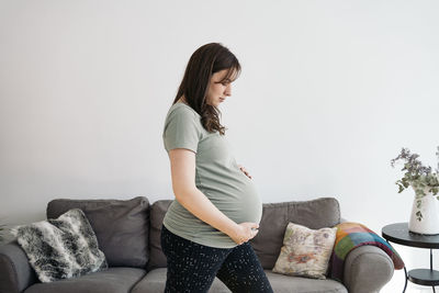 Woman sitting on sofa against wall at home