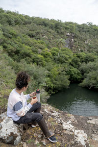 Woman drinking mate while relaxing sitting outdoors in nature.