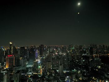 Illuminated buildings in city against sky at night