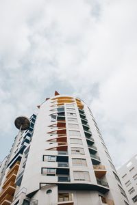 Low angle view of modern building against cloudy sky