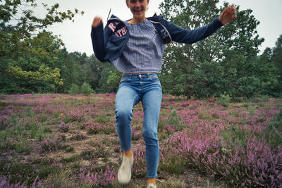 Portrait of woman running on land amidst flowering plants