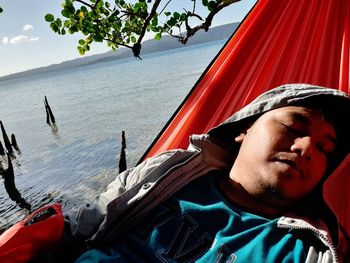 Close-up of man sleeping on hammock over sea