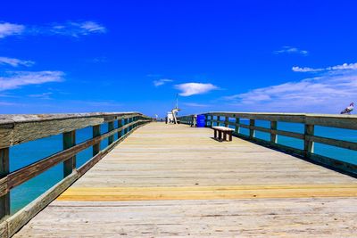 Pier on beach against blue sky