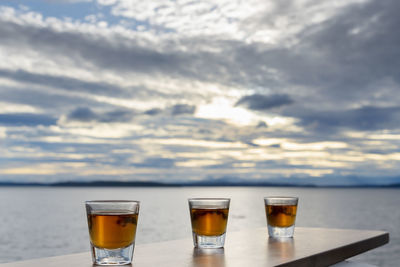 Three shots of alcohol over the sea in evening light outside deck view.