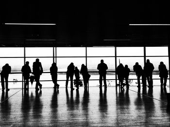 Silhouette people standing at window in airport