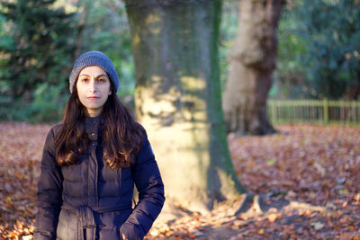 Portrait of woman standing at park during autumn
