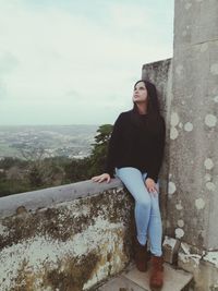 Portrait of young woman standing against rock