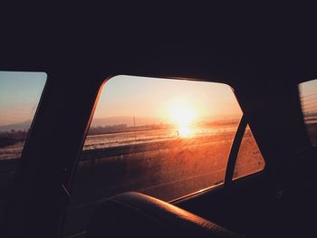 Close-up of side-view mirror against sky during sunset