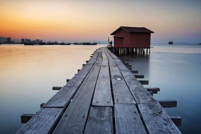 Wooden pier over lake against sky during sunset