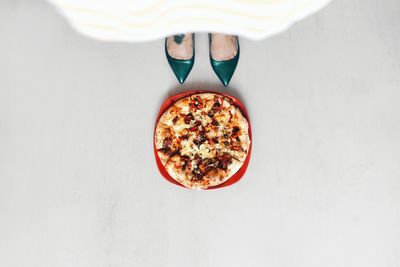 Low section of woman standing by pizza on tiled floor 