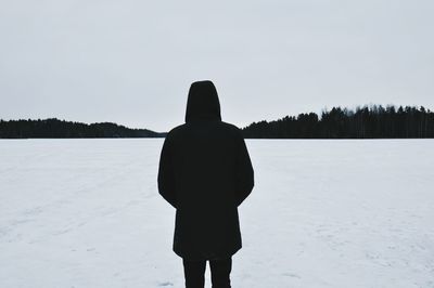 Rear view of man standing on snow covered field