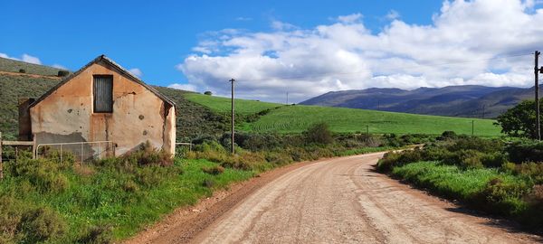 Road amidst field against sky