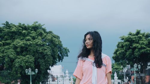 Young woman looking away against clear sky