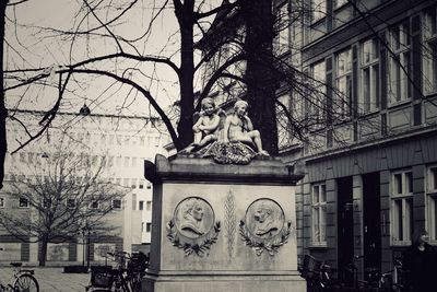 Statue against bare trees in city