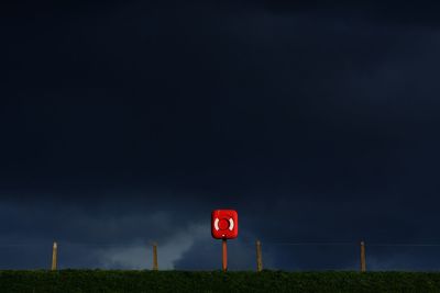 Life belt sign on field against sky at night