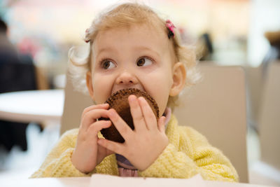 Cute baby girl eating cupcake at home