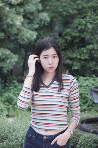 Portrait of beautiful young woman standing against plants