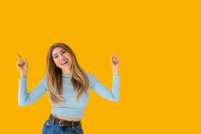 Portrait of young woman against yellow background